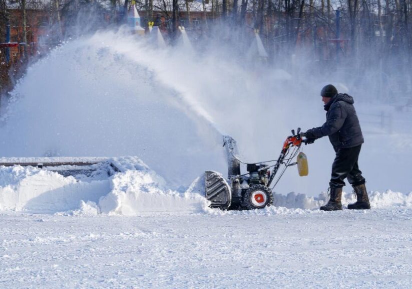 Person using a snow blower on a parking lot