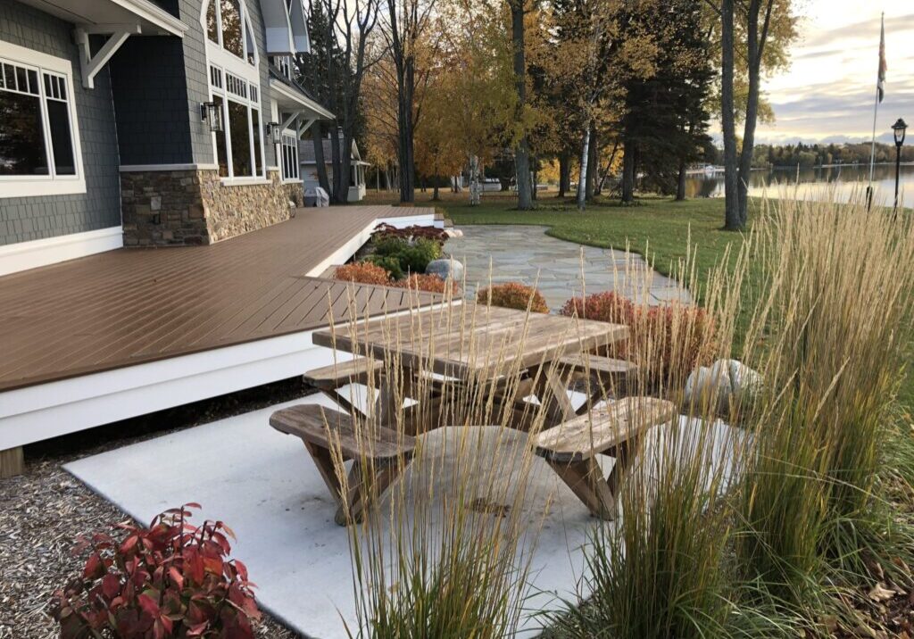 gallery2-scaled Outdoor picnic table near a lakeside house with ornamental grass and shrubs
